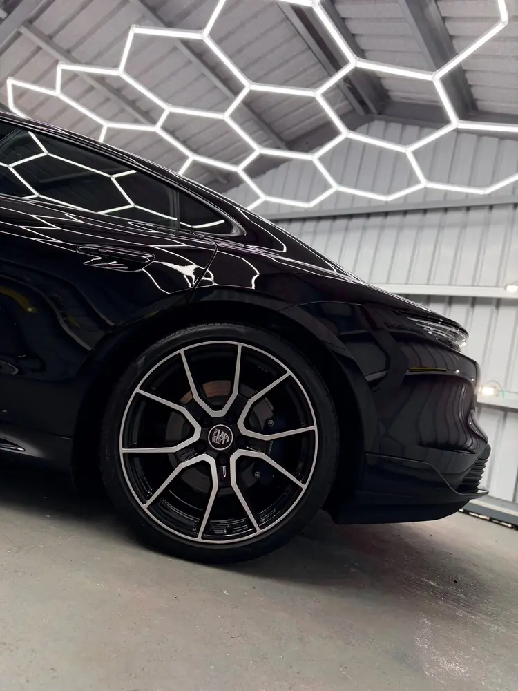 Black Porsche with a mirror-gloss finish under hexagonal lights in the Ongar detailing unit