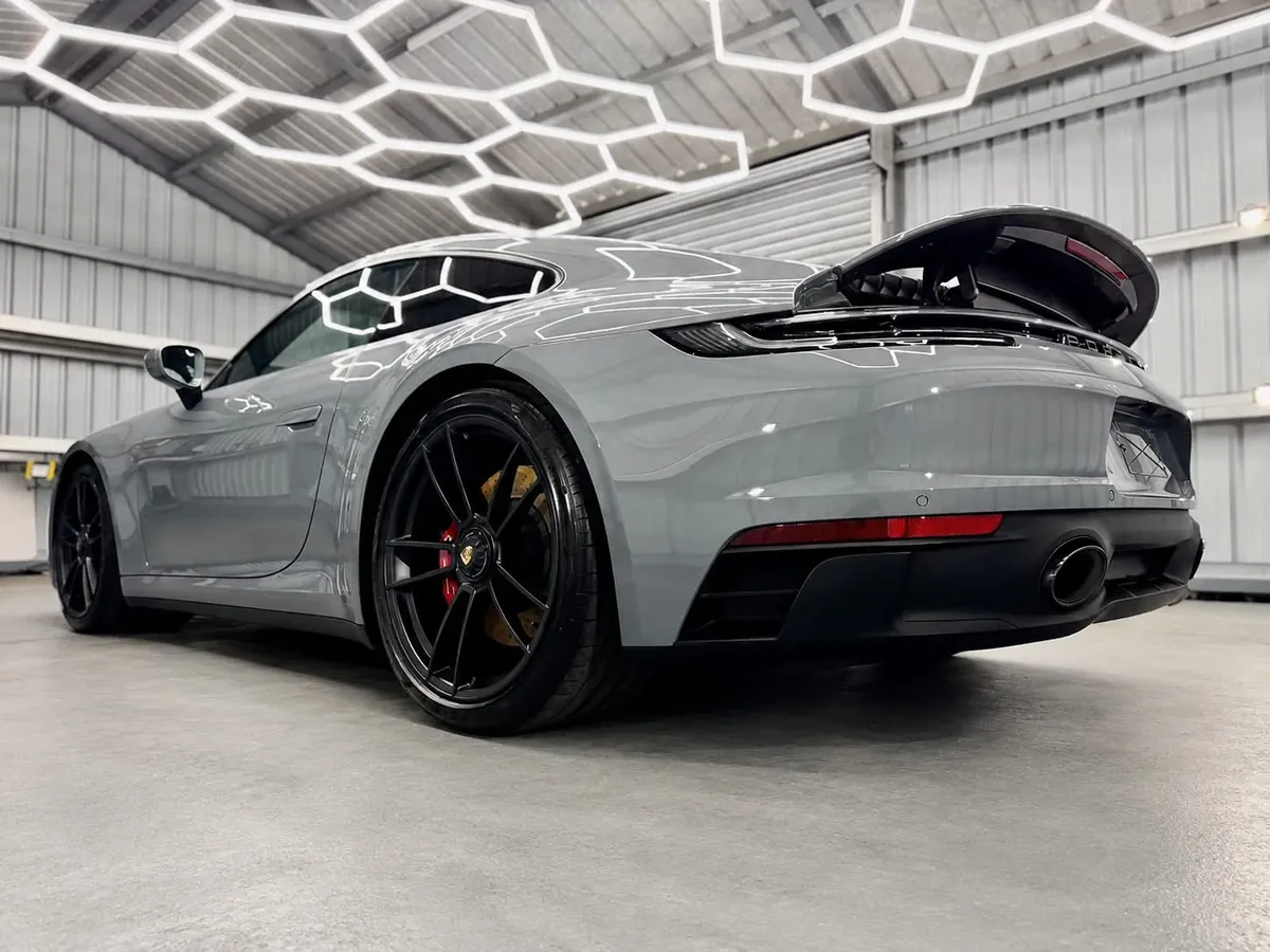 Grey Porsche 911 with paint protection film under hexagonal lights in the Day One Detailing unit