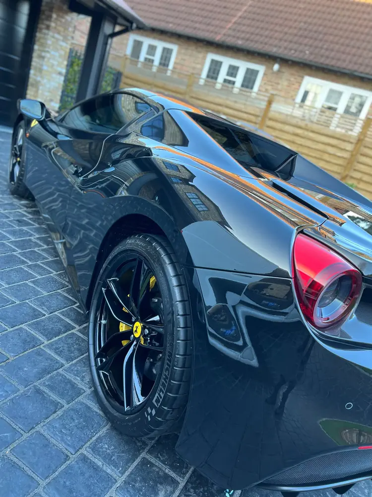 Glossy black Ferrari rear wheel and bodywork close-up