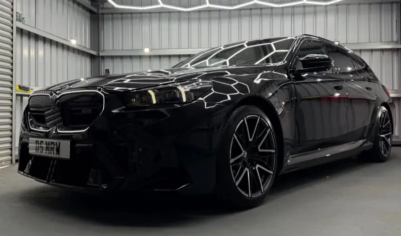 Black BMW M5 Touring under hexagonal lights in the Day One Detailing unit